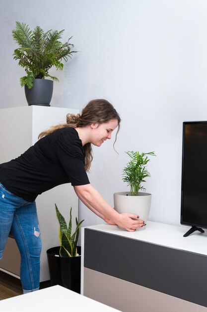 Mujer joven poniendo plantas en su nueva casa