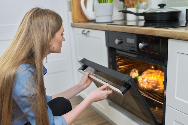 Mujer joven poniendo pollo marinado en una bolsa para hornear en el horno