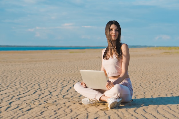 Mujer joven con el portátil en la playa