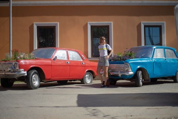 Una mujer joven posa en un automóvil abandonado con un jardín de flores en lugar del motor