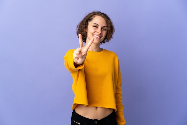 Mujer joven posando aislada contra la pared en blanco