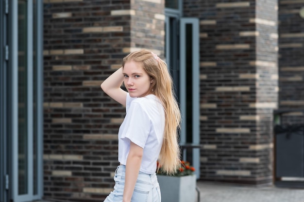 Mujer joven posando arreglando su cabello en una calle de la ciudad