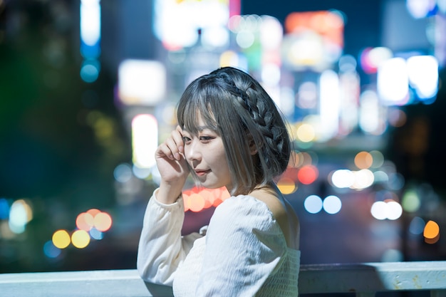 Mujer joven posando en el brillante paisaje urbano de Tokio