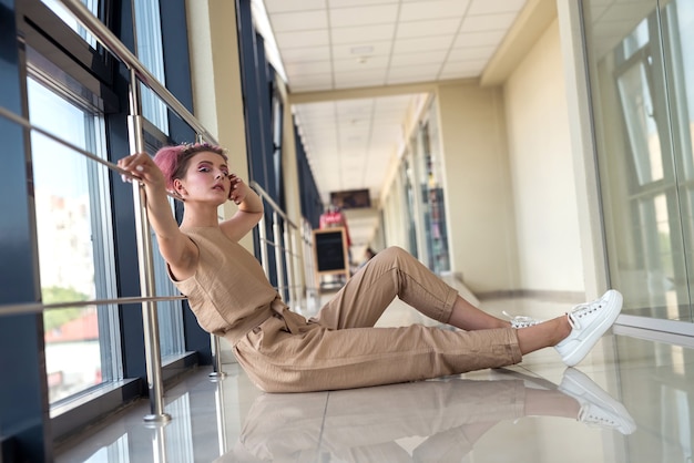 Mujer joven posando en cámara sentada en el suelo en el pasillo