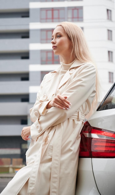 Mujer joven posando cerca de su coche blanco moderno