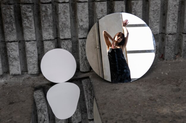 Mujer joven posando con espejo creando hermosos reflejos