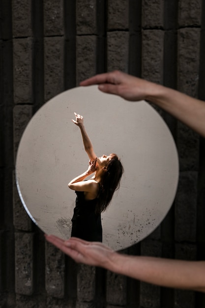 Mujer joven posando con espejo creando hermosos reflejos