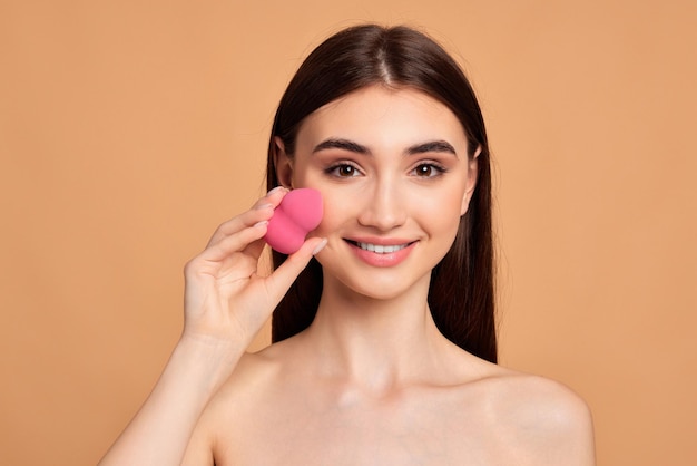 Foto mujer joven posando con esponjas cosméticas rosas