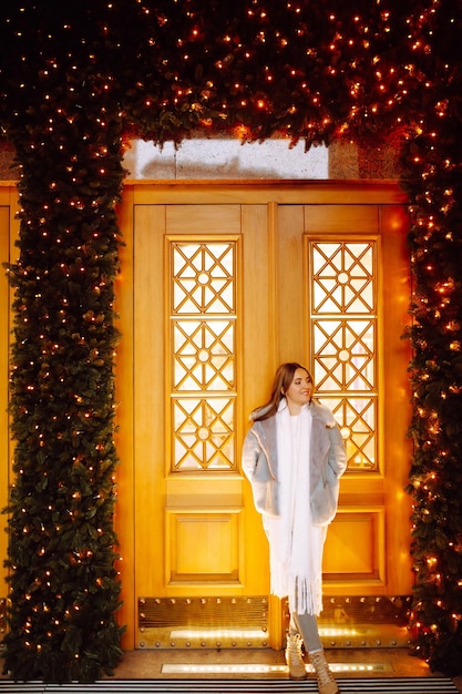 Mujer joven posando junto al árbol de Navidad en vacaciones de invierno con estrella de Navidad.
