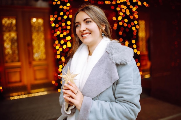 Mujer joven posando junto al árbol de navidad en vacaciones de invierno con estrella de navidad