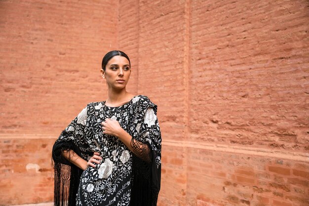 Foto mujer joven posando con un mantón español tradicional en la calle