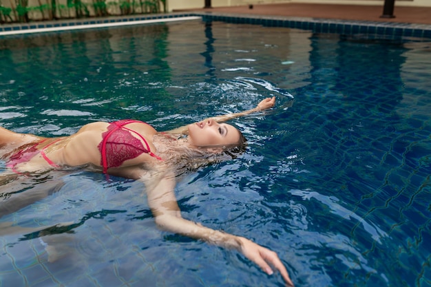 Mujer joven posando mientras está acostado en una piscina al aire libre