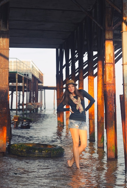 Mujer joven posando bajo el muelle.