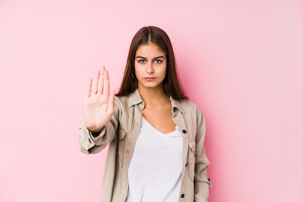 Mujer joven posando y de pie con la mano extendida que muestra la señal de stop