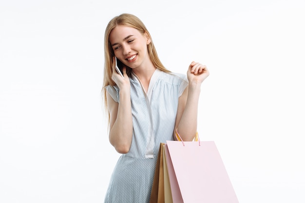 Mujer joven posando con teléfono, con bolsas de compras