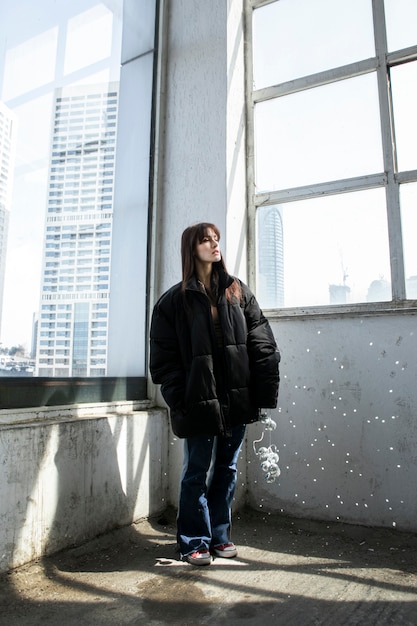 Foto mujer joven, posar, con, espejo, dentro, edificio, al lado de, ventana