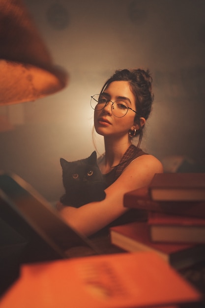 Foto mujer joven, posar, y, tenencia, gato negro