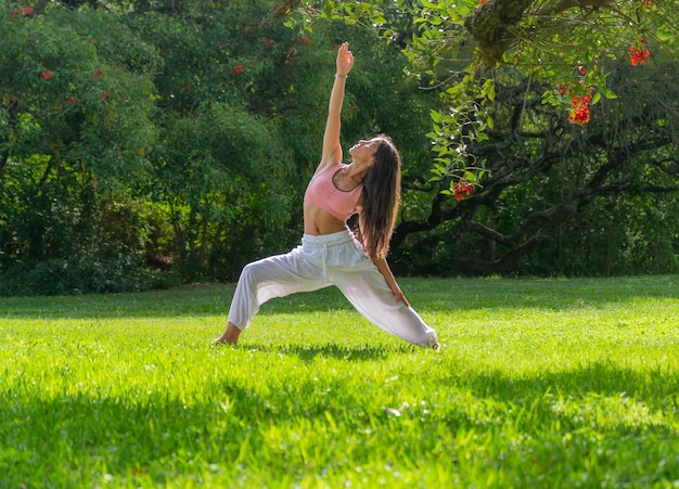 Mujer joven en pose de guerrero practicando yoga en un concepto de Green ParkWellness