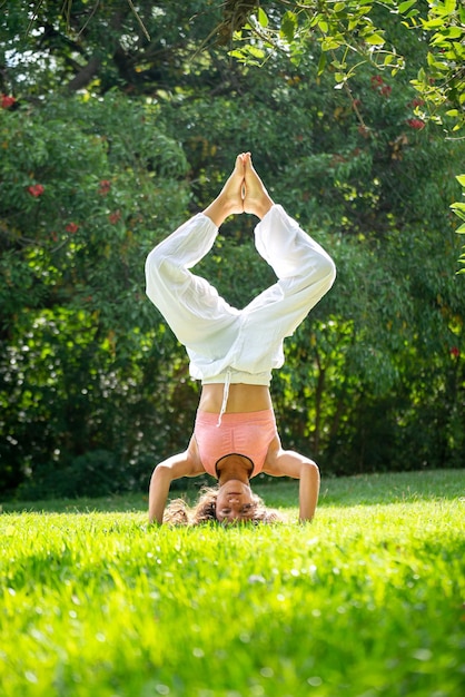 mujer joven, posición, en, ella, cabezas, hacer, yoga, en, un, verde, parkvertical, imagen