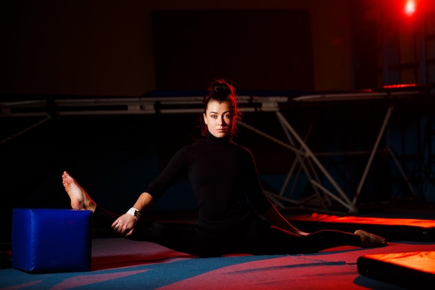 La mujer joven practica la sentada del hilo. Chica atlética haciendo gimnasia en el gimnasio. Estilo de vida activo