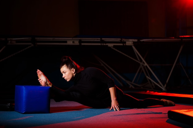 La mujer joven practica la sentada del hilo. Chica atlética haciendo gimnasia en el gimnasio. Estilo de vida activo