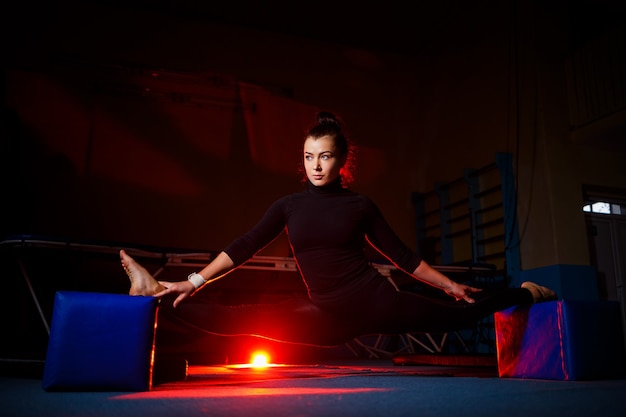 La mujer joven practica la sentada del hilo. Chica atlética haciendo gimnasia en el gimnasio. Estilo de vida activo