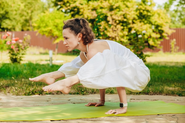 Mujer joven practica yoga en el patio de una casa de campo