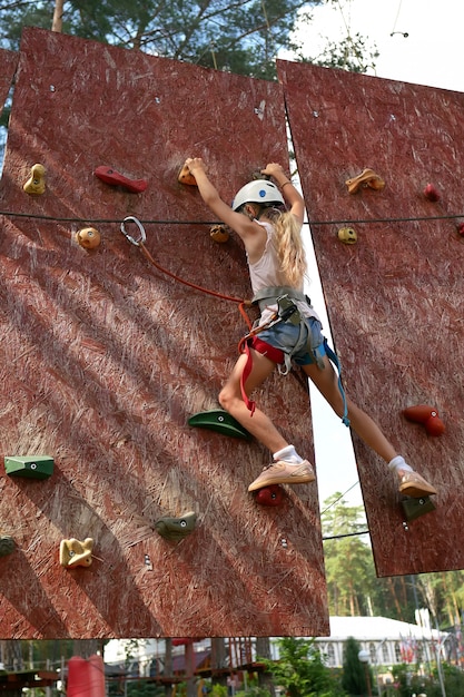 Mujer joven practicando escalada en una pared de roca en el interior