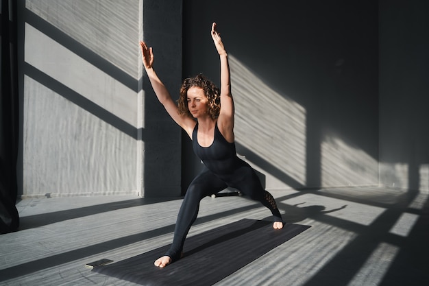Mujer joven practicando posturas de yoga en un fondo urbano en un día soleado