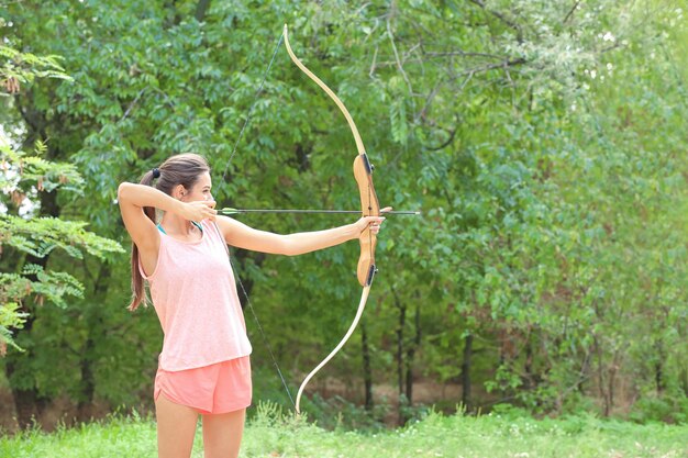 Mujer joven practicando tiro con arco al aire libre