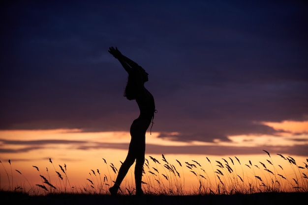 Mujer joven practicando yoga al aire libre por la noche