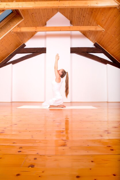 Una mujer joven practicando yoga en un ático Studio.