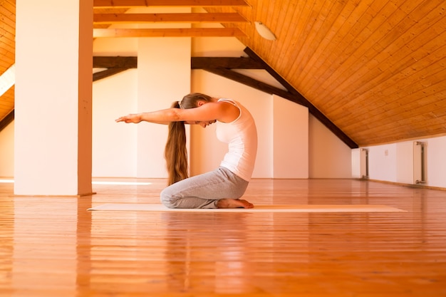 Una mujer joven practicando yoga en un gran ático Studio.