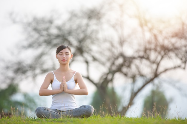 Mujer joven practicando yoga en el parque al aire libre. meditación.