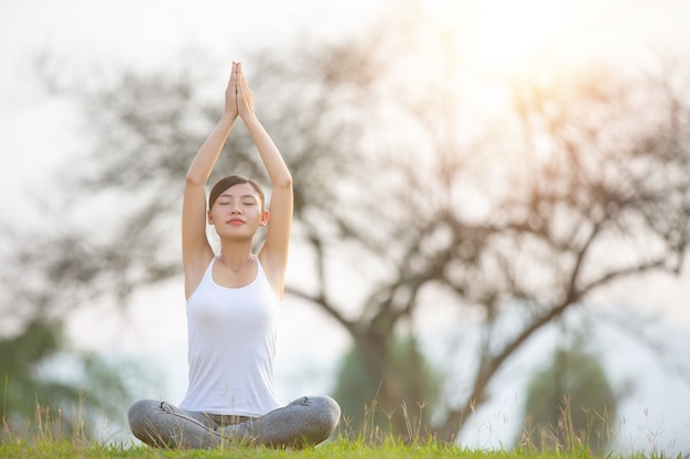 Mujer joven practicando yoga en el parque al aire libre. Meditación.