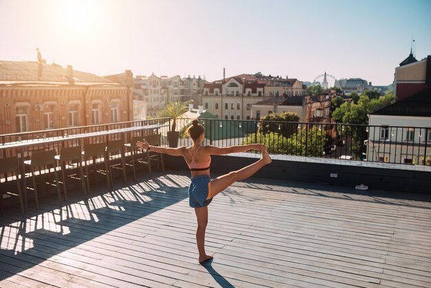 Mujer joven practicando yoga en el techo de un edificio