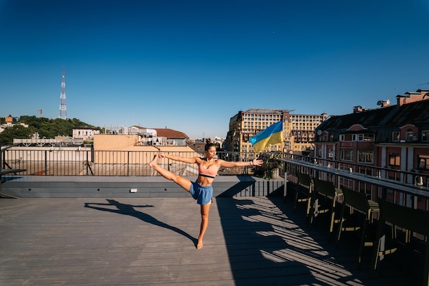 Mujer joven practicando yoga en el techo de un edificio