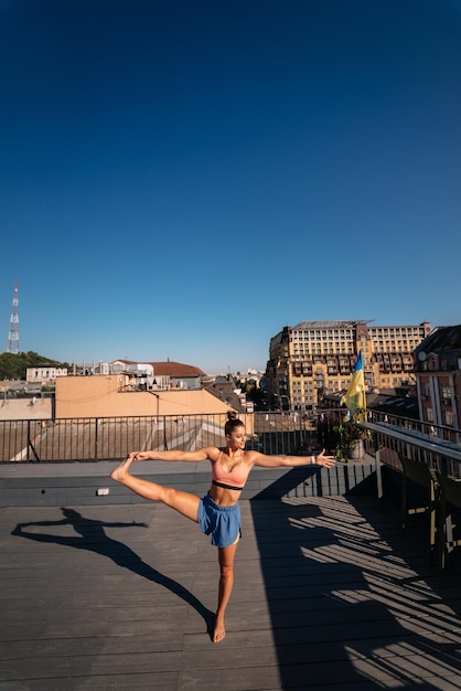 Mujer joven practicando yoga en el techo de un edificio