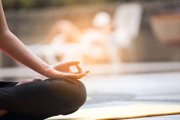 Mujer joven practicar yoga junto a la piscina.