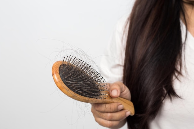 Mujer joven preocupada por la pérdida de cabello en un fondo blanco