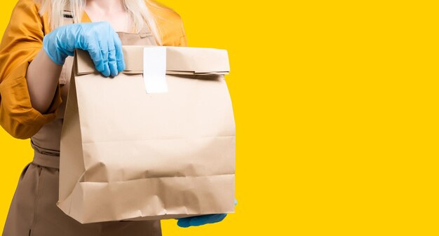 Mujer joven preparando comida orgánica para llevar dentro de un restaurante sin plástico durante el brote de Coronavirus - Trabajadora dentro de la cocina cocinando comida para el servicio de entrega en línea.