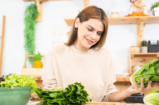 Mujer joven preparando comida saludable con ensalada de verduras mujer sentada en la despensa en una hermosa cocina interior La comida de dieta limpia de productos e ingredientes locales Mercado fresco