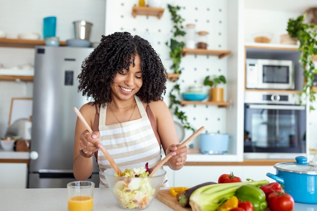 Mujer joven preparando ensalada de verduras en su cocina Concepto de estilo de vida saludable mujer hermosa con vegetales mixtos