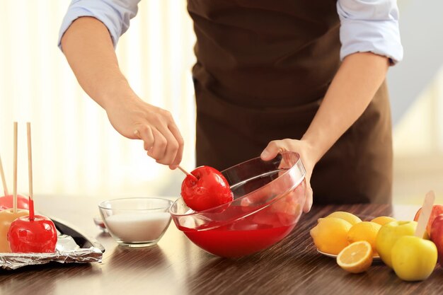 Foto mujer joven preparando manzanas de caramelo en la cocina