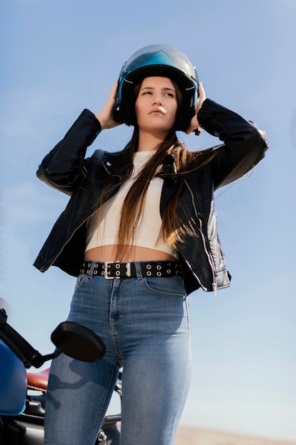 Foto mujer joven preparándose para andar en motocicleta en la ciudad