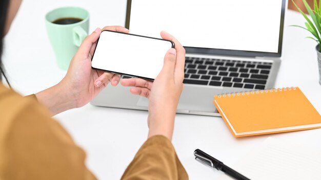 Mujer joven del primer que sostiene smartphone con la pantalla aislada.