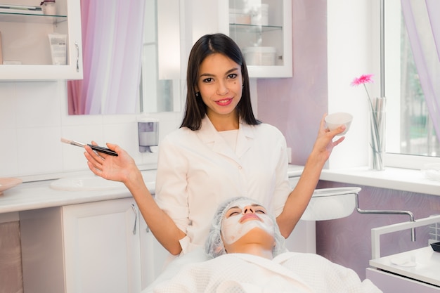 Mujer joven en procedimientos de spa aplicando mascarilla