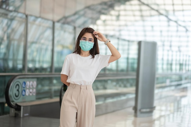 Mujer joven con protección de máscara facial Infección por enfermedad de coronavirus feliz mujer asiática viajera Tiempo para viajar después del concepto de dosis de refuerzo de la vacuna