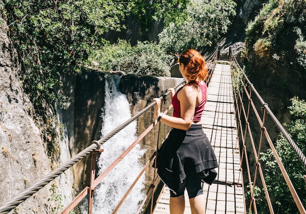 Mujer joven en un puente colgante caminando por la ruta de Los Cahorros, Granada, España