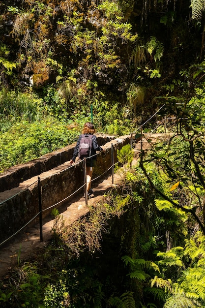Una mujer joven en un puente en el sendero Levada do Caldeirao Verde Queimadas Madeira